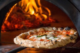 Pizza wird aus Steinofen geholt